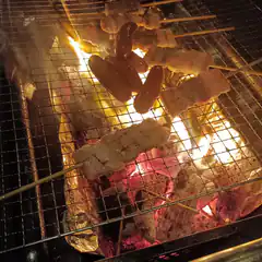 Sausages and meat skewers grilling over hot coals