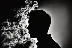 Silhouette of man exhaling smoke