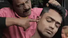 Man picking earwax from another man's ear