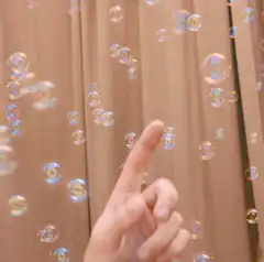 Hand popping soap bubbles