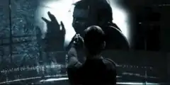 Man raises arms in front of glowing screen