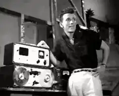 Man laughing next to reel-to-reel tape recorder