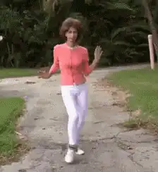 Woman in pink cardigan dancing on path