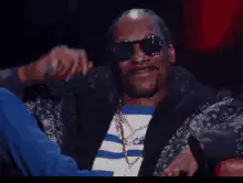 Snoop Dogg nodding and adjusting sunglasses