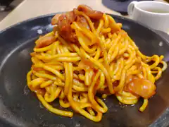 Spaghetti with sausage on a black plate