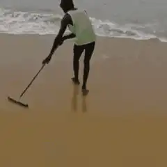 person sweeping sand on beach
