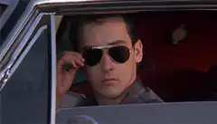 John Cusack adjusts sunglasses and yawns