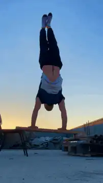 Man doing handstand pushups on wooden planks
