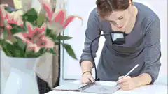 Artist drawing lilies with magnifying glass