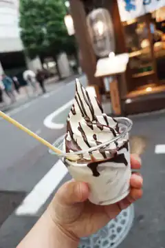hand holding soft serve ice cream with chocolate drizzle