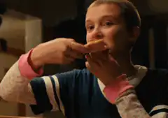 Eleven eating pizza and looking surprised