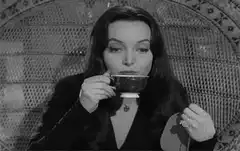 Morticia Addams sipping tea