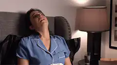 Woman in blue pajamas laughing in bed