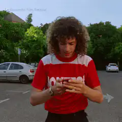 Man in red shirt texting in parking lot