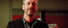 Dr. House raises a martini glass