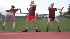 Three men doing the Macarena on a track