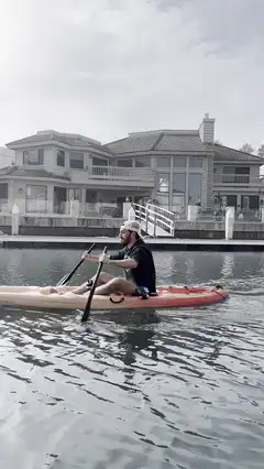 Man kayaking past waterfront mansions