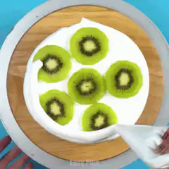 Decorating a kiwi cake with frosting