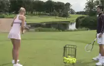 Woman hits golf ball with tennis racket