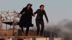 Two people running on a rooftop at sunset