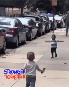 Two toddlers run and hug on sidewalk