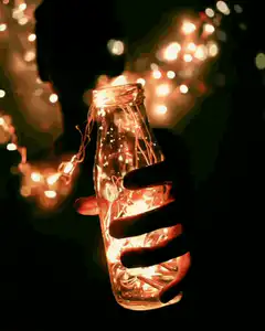 Hand holding a bottle with fairy lights