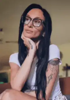 Woman with glasses and tattoos tilting head