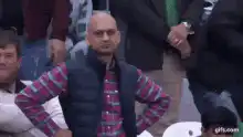 Bald man in vest looks around confused