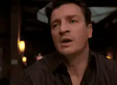 Nathan Fillion shrugs and rests his head on his hand