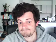 Man smirking in grey hoodie