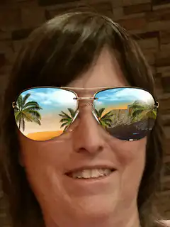 Woman with tropical beach reflection in sunglasses