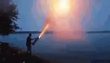 Person with flamethrower by the water