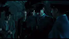 Officer shushes prisoners in dark room