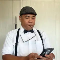 man with glasses in mouth looking at phone