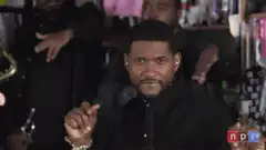 Usher making hand gestures and smiling