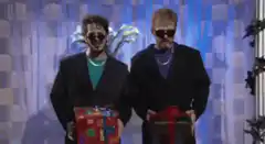 Two men in sunglasses holding gifts dancing