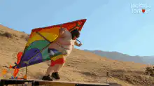Man in rainbow wings flying over hill