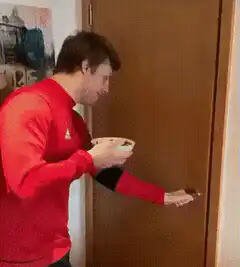 Man in red sweater opens door and walks in