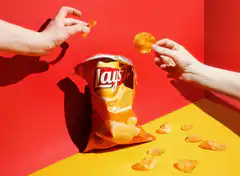 Hands grabbing Lay's chips from bag