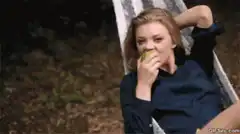 Natalie Dormer eating an apple in a hammock