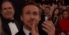Ryan Gosling clapping with a smile