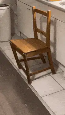 Hand pushes wooden chair until it breaks