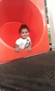 Baby slides down red tube slide