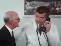 Man on phone pats bald man's head