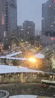 Snow falling on city street at night