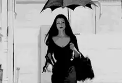 Wednesday Addams walking with bat umbrella