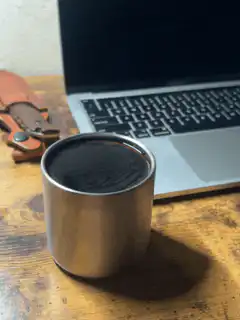 Metal cup with dark liquid on desk