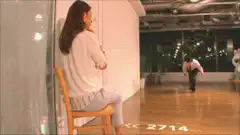 Woman sits on chair as man bows on floor