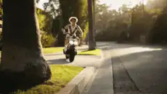 Man riding scooter on sidewalk