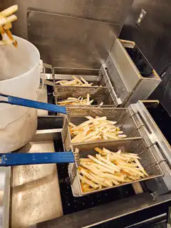 Worker frying french fries in a commercial kitchen
